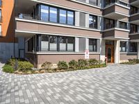 a brick driveway leading to an apartment building with a parking meter in front of it