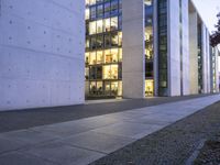 a tall building with some glass windows next to a sidewalk with people walking by it