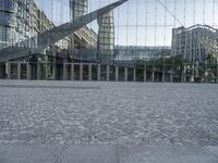 a brick walkway with a large sculpture outside of the building and buildings that line it