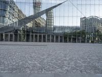 a brick walkway with a large sculpture outside of the building and buildings that line it