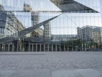 a brick walkway with a large sculpture outside of the building and buildings that line it