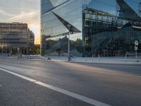 an empty city street next to glass and steel buildings with two bikes parked beside the road