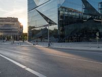 an empty city street next to glass and steel buildings with two bikes parked beside the road