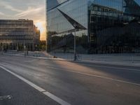 an empty city street next to glass and steel buildings with two bikes parked beside the road