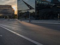 an empty city street next to glass and steel buildings with two bikes parked beside the road