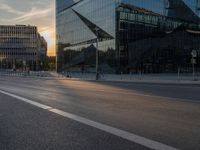 an empty city street next to glass and steel buildings with two bikes parked beside the road