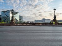 an empty street and a bridge on a cloudy day, with skyscrapers in the background