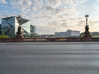 an empty street and a bridge on a cloudy day, with skyscrapers in the background