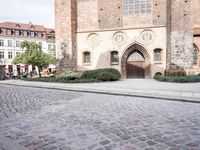 a person on a bike walking by an old building with an archway and a sign