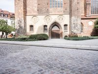 a person on a bike walking by an old building with an archway and a sign