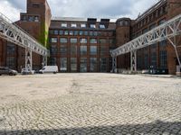 brick pavement with metal frame and white structure in front of tall building, outside, on cloudy day