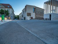 empty street lined with cement buildings next to a tall building with a staircase up to it