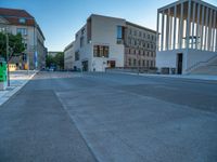 empty street lined with cement buildings next to a tall building with a staircase up to it