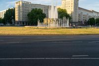 the city has water spouts in the fountain on the side of the road and on the other side, the road is very empty