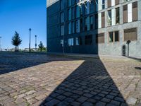 an empty brick street and the shadow of a building is cast on it by the sun