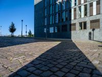 an empty brick street and the shadow of a building is cast on it by the sun