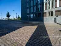 an empty brick street and the shadow of a building is cast on it by the sun