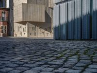 cobblestone driveway surrounded by modern buildings on sunny day with sun reflecting onto the windows