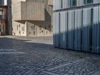 cobblestone driveway surrounded by modern buildings on sunny day with sun reflecting onto the windows