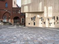 there is a brick walkway with a staircase going up it and three building in the background