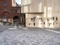 there is a brick walkway with a staircase going up it and three building in the background