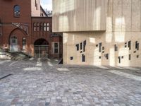 there is a brick walkway with a staircase going up it and three building in the background