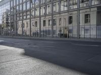 a large building is reflected in the side of the street that goes along this narrow road