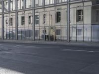 a large building is reflected in the side of the street that goes along this narrow road