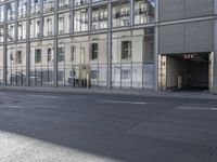 a large building is reflected in the side of the street that goes along this narrow road