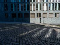 a street view with a brick surface between some buildings and green grass in the foreground