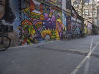 bicycles parked next to a wall with graffiti on it in a city lane filled with bikes