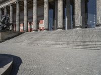 the man is riding his bicycle on the steps outside of the building and holding a bag