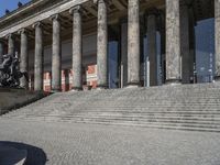 the man is riding his bicycle on the steps outside of the building and holding a bag