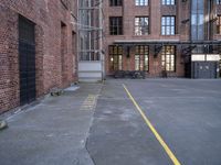 a view down an empty parking lot with two bicycles parked in the street below a large brick building