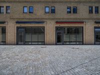 the sidewalk is paved with stones and has a bench in front of it, with no people inside