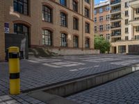 a brick courtyard has steps leading up to it, and a blue umbrella is on the ground