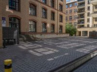 a brick courtyard has steps leading up to it, and a blue umbrella is on the ground