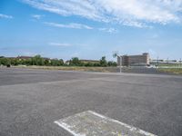 a skate board with wheels on an empty parking lot with buildings in the background and sky