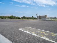 a skate board with wheels on an empty parking lot with buildings in the background and sky