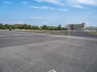 a skate board with wheels on an empty parking lot with buildings in the background and sky