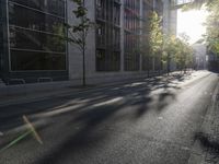 a long road next to some very tall buildings in the sun with a light at one end