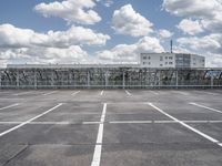 an empty parking lot with a fence around it and several buildings in the background of this image