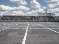 an empty parking lot with a fence around it and several buildings in the background of this image