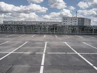 an empty parking lot with a fence around it and several buildings in the background of this image