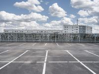 an empty parking lot with a fence around it and several buildings in the background of this image