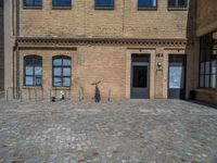 the sidewalk is paved with stones and has a bench in front of it, with no people inside