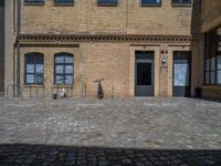 the sidewalk is paved with stones and has a bench in front of it, with no people inside