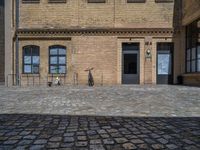 the sidewalk is paved with stones and has a bench in front of it, with no people inside