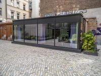 an empty parking lot with plants in the ground and on the side of the building, there is an enclosed area and windows