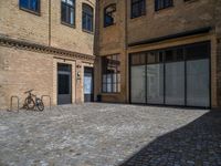 the sidewalk is paved with stones and has a bench in front of it, with no people inside